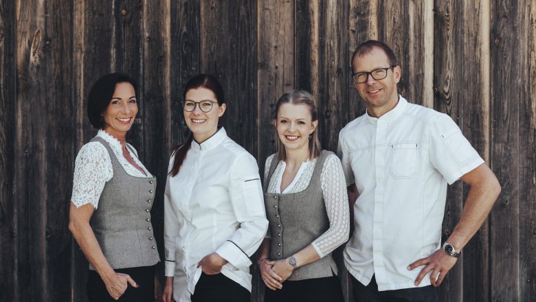 Host family Mathe: Bianca, Tanja, Julia and Andreas, © Niederösterreich Werbung/David Schreiber Four people are standing in front of a wooden wall, two women in traditional costume and two people in white clothing.