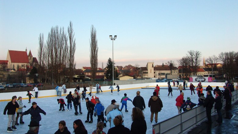 Ice rink in Eggenburg, © Donner Karl People skating on an open-air ice rink with a church in the background.