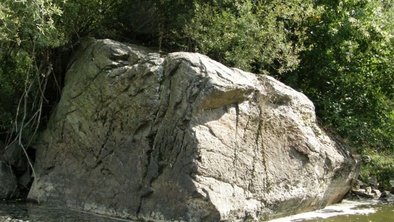 Flusslehrpfad "Hangenstein", © Gemeinde Karlstein Großer Felsen am Ufer eines Flusses, umgeben von Bäumen.