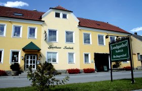 Landgasthof Surböck, © Landgasthof Surböck Gelbes Gebäude mit der Aufschrift 'Gasthaus Surböck' und einem grünen Schild 'Landgasthof Surböck Rodingersdorf'.