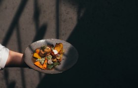 Waldviertler Küche modern interpretiert, © Niederösterreich Werbung/Daniela Führer Ein Teller mit modern interpretierter Waldviertler Küche, präsentiert von einer Hand vor einem dunklen Hintergrund.