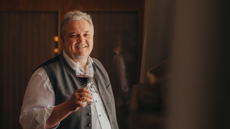 Landlord Karl Schwaighofer, © Niederösterreich Werbung/Daniela Führer A smiling man in traditional dress holds a glass of red wine.