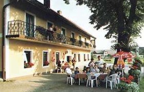 Gasthof - Pension "Zur Linde", © Gasthof - Pension "Zur Linde" Ein Gasthof mit Terrasse, auf der Menschen an Tischen sitzen, umgeben von Sonnenschirmen und Blumen.