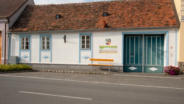 Freizeitmuseum Langau, © Freizeitmuseum Langau Ein kleines, traditionelles Gebäude mit roten Ziegeln und blauen Fensterrahmen. Vor dem Gebäude steht eine gelbe Bank mit der Aufschrift 'Reserviert für DICH!'.