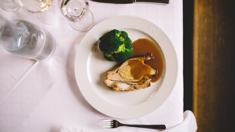 Favorite on the menu: Stuffed breast of veal, © Niederösterreich Werbung/Mara Hohla Stuffed veal breast with broccoli and sauce on a white plate.