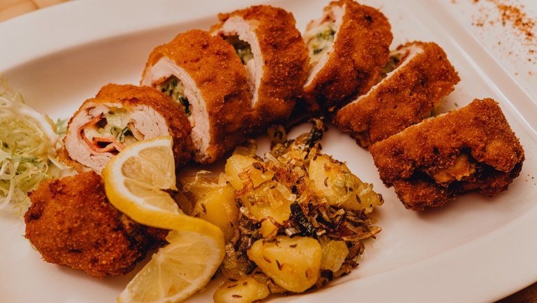 Gefülltes gebackenes Putenfilet, © Niederösterreich Werbung/Klaus Engelmayer Gefülltes gebackenes Putenfilet mit Kartoffelbeilage und Zitronenscheiben auf einem weißen Teller.