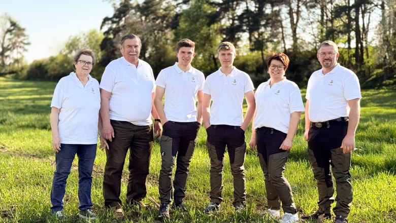 Haidl family, © Familie Haidl Six people in white polo shirts are standing on a meadow in front of trees.