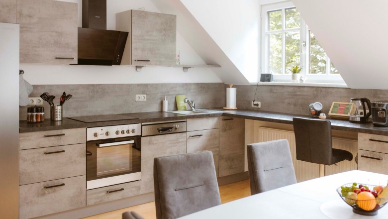 Küche, © Katja Koppensteiner Fotografie Moderne Küche mit grauen Schränken, Esstisch und Obstschale.