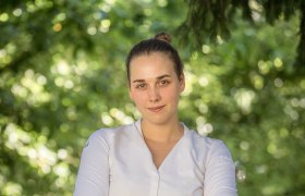 Küchenchefin Victoria Kuben, © Stephan Mussil Eine Frau in weißem Hemd steht mit verschränkten Armen vor einem unscharfen, grünen Hintergrund.