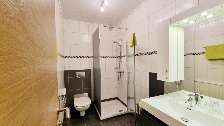Badezimmer, © Café Pension Kristall Modernes Badezimmer mit Dusche, Waschbecken und Toilette.