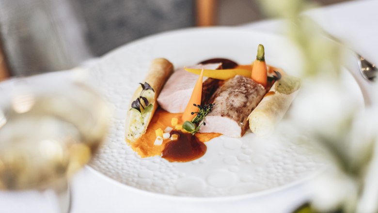 Pink fillet of Danube country pork, young vegetables, crispy potato roll, © Niederösterreich Werbung/David Schreiber Gourmet dish with pork fillet, vegetables and potato roll on a white plate.