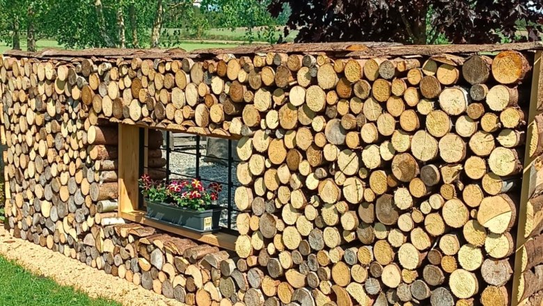Garden of 100 roses, B.Scherzer, © Garten der 100 Rosen, B.Scherzer Wooden wall with window and flower box, surrounded by trees and lawn.