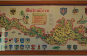 Landkarte_Heimatstube, © Gemeinde Reingers Landkarte von Südmähren mit Wappen und Illustrationen in einem Holzrahmen.