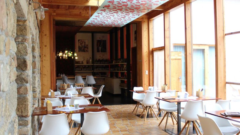 Heuriger Kainz, © Heuriger Kainz Innenansicht eines modernen Restaurants mit weißen Stühlen und Holztischen.