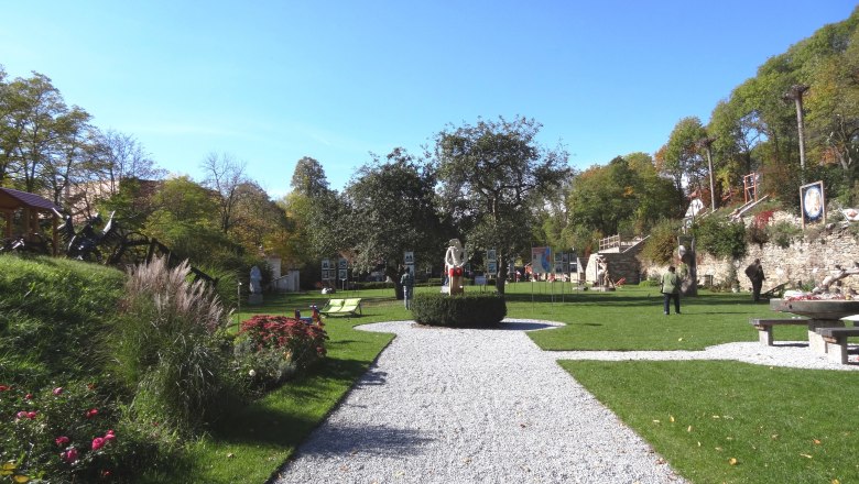 Karikaturengarten Brunn am Wald, © Marktgemeinde Lichtenau Ein gepflegter Garten mit Skulpturen und Spaziergängern bei sonnigem Wetter.