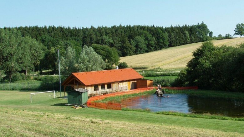 swimming_pond_brunn_am_wald, © Gemeinde Lichtenau A small bathing pond with a wooden building and surrounding fields and woods.