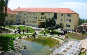 Innenhof, © Gästehaus der LK-Technik Mold Innenhof mit Teich, Sitzbereich und Menschen.