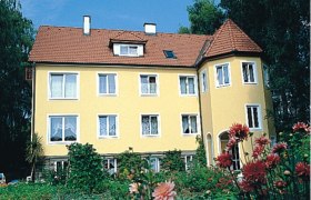 Privatzimmer Mayer, © Privatzimmer Mayer Gelbes Haus mit rotem Dach und Garten im Vordergrund.
