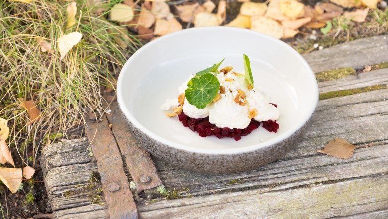 Autumn horseradish mousse, © Franz Kuben A plate of horseradish mousse on beet, garnished with walnuts and green leaves, stands on a rustic wooden table with autumn leaves.