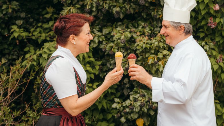 Eis, Teigwaren, Chutneys – alles von Hand gemacht, © Niederösterreich Werbung/Daniela Führer Zwei Personen halten Eistüten und lächeln sich an, vor einem Hintergrund aus grünen Blättern.