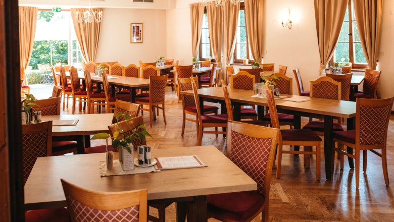 Gemütlich speisen oder festlich dinieren, © Niederösterreich Werbung / Daniela Führer Ein gemütlich eingerichtetes Restaurant mit Holztischen und gepolsterten Stühlen, dekoriert mit Pflanzen und Menükarten.