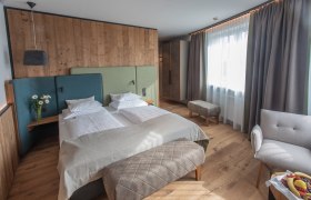 Sole Felsen Hotel, © Sole Felsen Welt, Peter Baier Modernes Hotelzimmer mit Doppelbett, Holzwänden und großen Fenstern.