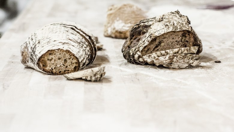 Erste Waldviertler Bio-Backschule, © Erste Waldviertler Bio-Backschule, Andrea Peller Zwei Laibe Brot auf einem Holztisch, teilweise geschnitten.