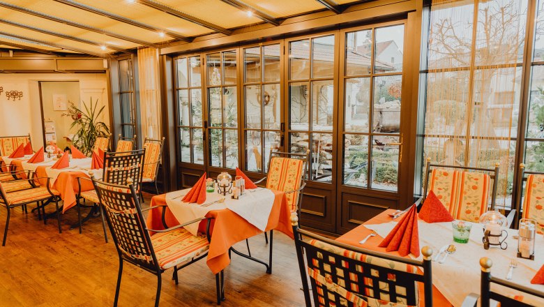 Winter- und Gastgarten, © Niederösterreich Werbung/Klaus Engelmayer Ein gemütlicher Wintergarten mit gedeckten Tischen und Stühlen, umgeben von großen Fenstern mit Blick nach draußen.