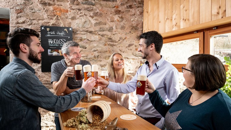Wirtshausbrauerei Haselböck, © Waldviertel Tourismus, Studio Kerschbaum Gruppe von Menschen stößt mit Bierkrügen in einer rustikalen Brauerei an.