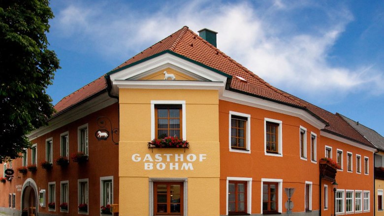 Gasthof Böhm, © GH Böhm Ein traditionelles Gasthaus mit orange-gelber Fassade und roten Dachziegeln unter blauem Himmel.