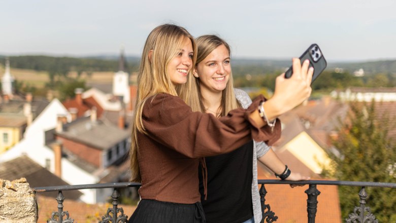 Weitra, © Benjamin Wald Zwei Frauen machen ein Selfie auf einem Balkon mit Blick auf eine Stadt.