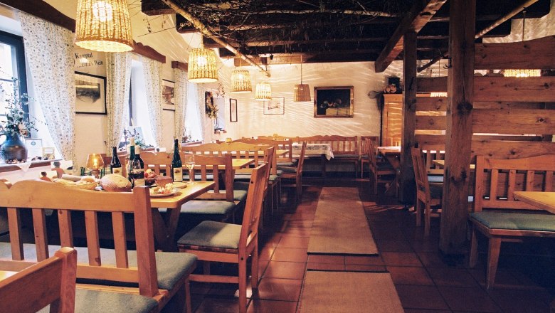 Wine tavern Rebstockgrill Höfinger, © Weingut Höfinger Cozy interior of a traditional wine tavern with wooden furniture and laid tables.