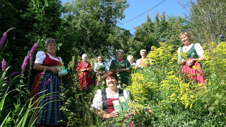 Kräutertanten Bad Traunstein, © Kräutertanten Bad Traunstein Frauen in traditioneller Kleidung stehen in einem Garten mit Kräutern und Blumen.