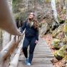 Eine Frau wandert auf einer Holztreppe in einem bewaldeten Gebiet.