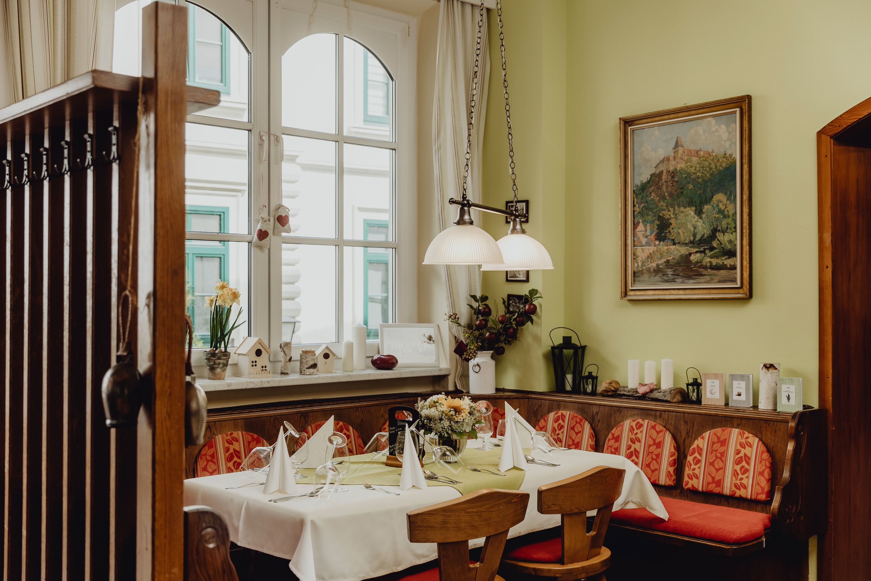 Gemütliche Gaststube mit gedecktem Tisch, Holzmöbeln und Dekorationen.