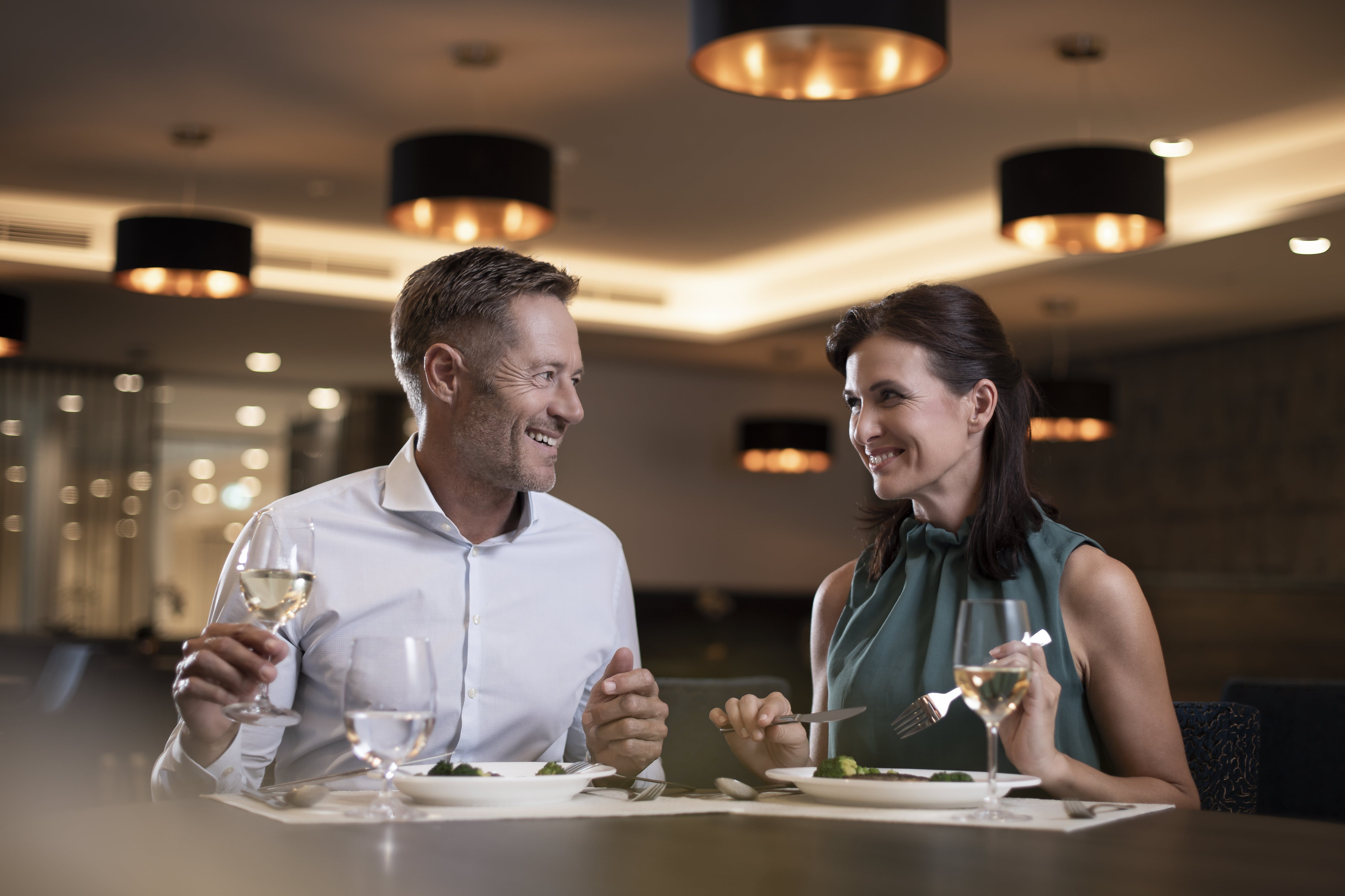 Ein Paar sitzt in einem eleganten Restaurant und genießt ein Abendessen mit Wein.