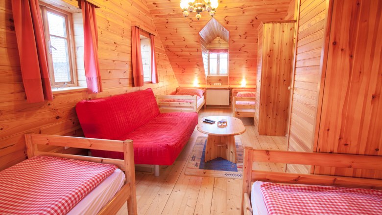 Holzvertäfeltes Zimmer mit roten Vorhängen und Möbeln.