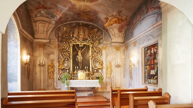 Innenansicht einer Kapelle mit kunstvoll verziertem Altar und Fresken an der Decke.