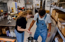 Zwei Personen in einer Werkstatt stellen Kerzen her.