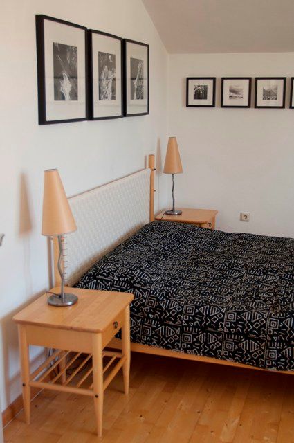 Schlafzimmer mit Doppelbett, Nachttischen und Wandbildern.
