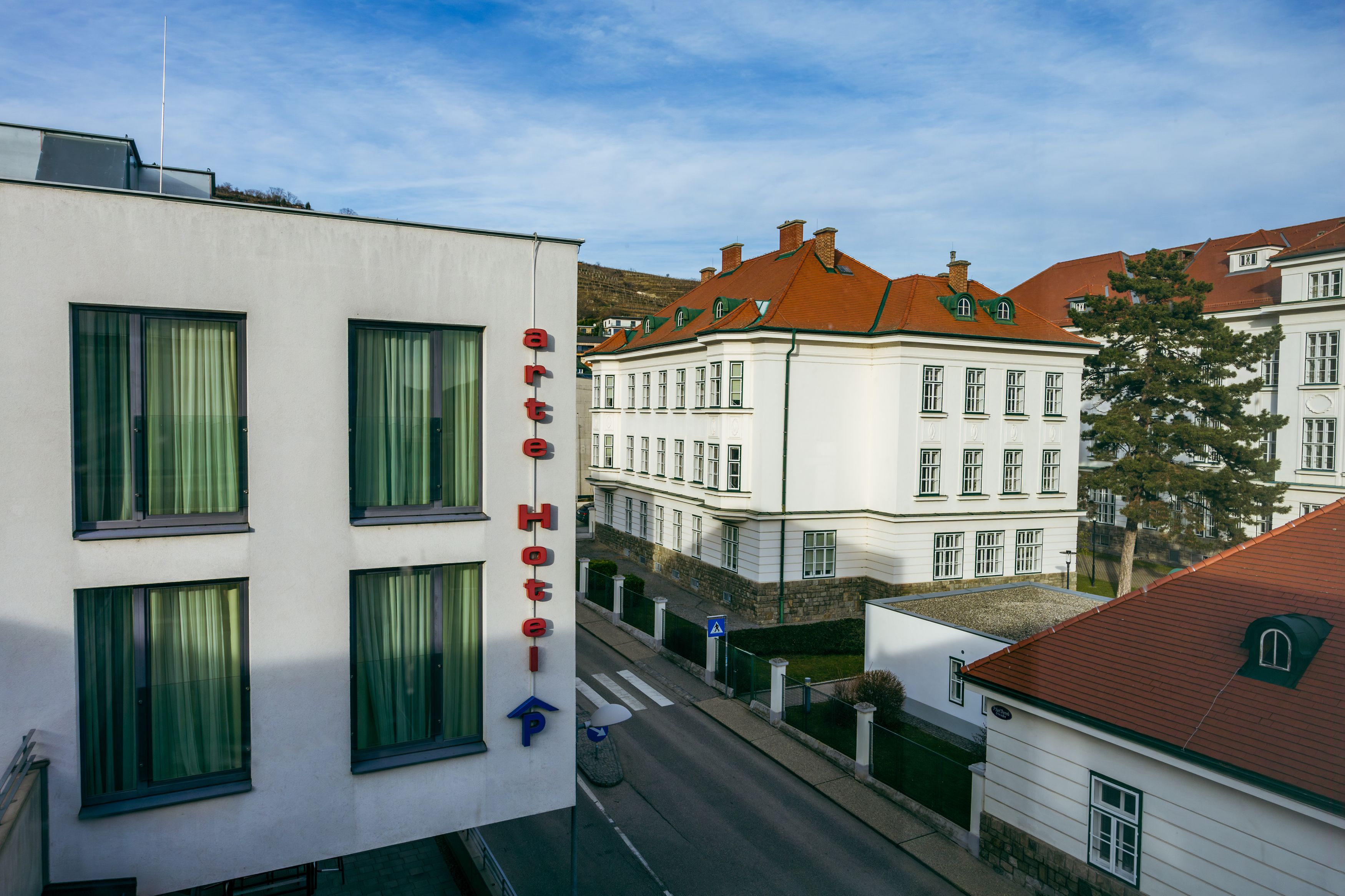 Außenansicht des arte Hotels in Krems mit umliegenden Gebäuden und Straße.