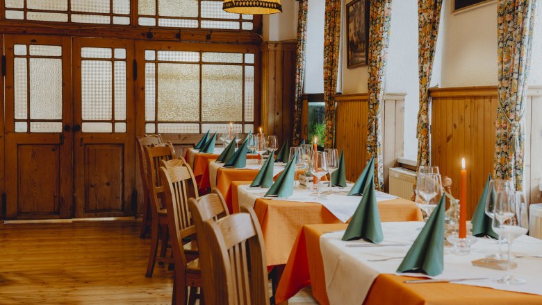 Ein Koch in schwarzer Uniform kocht in einer professionellen Küche mit mehreren Töpfen und Kellen an der Wand.