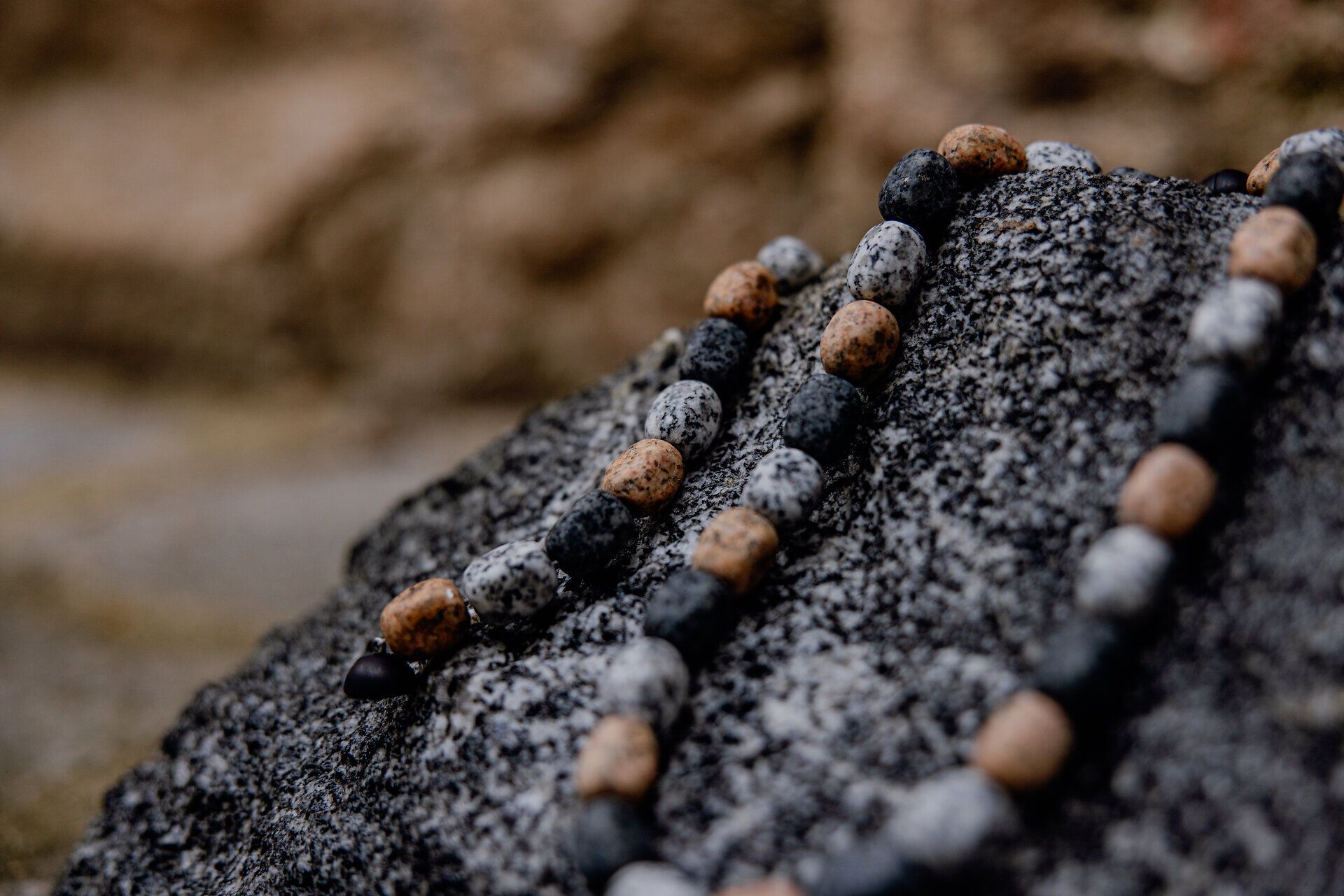 Die kunstvoll gestalteten Granitperlen liegen sanft auf dem rauen Stein, während die Natur im Hintergrund eine ruhige Atmosphäre schafft. Hier spürt man die Verbindung zwischen Handwerk und der majestätischen Landschaft des Waldviertels. Ein Ort, der die Sinne anregt und zur Entdeckung einlädt.