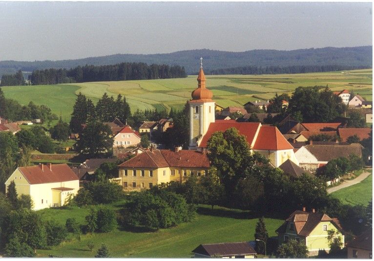 Luftaufnahme von Waldkirchen an der Thaya mit Kirche und umliegenden Häusern, umgeben von Feldern und Wäldern.