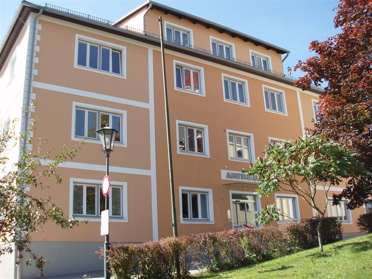 Ein dreistöckiges, orangefarbenes Gebäude mit weißen Fensterrahmen und einem Schild mit der Aufschrift 'Amtshaus'.