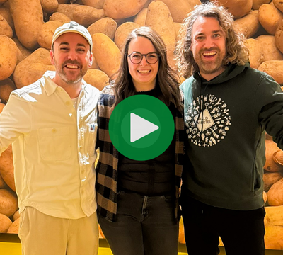 3 Personen lachend in die Kamera vor einer Fotowand mit Erdäpfeln