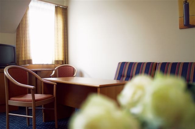 Hotelzimmer mit Tisch, Stühlen und Sofa.