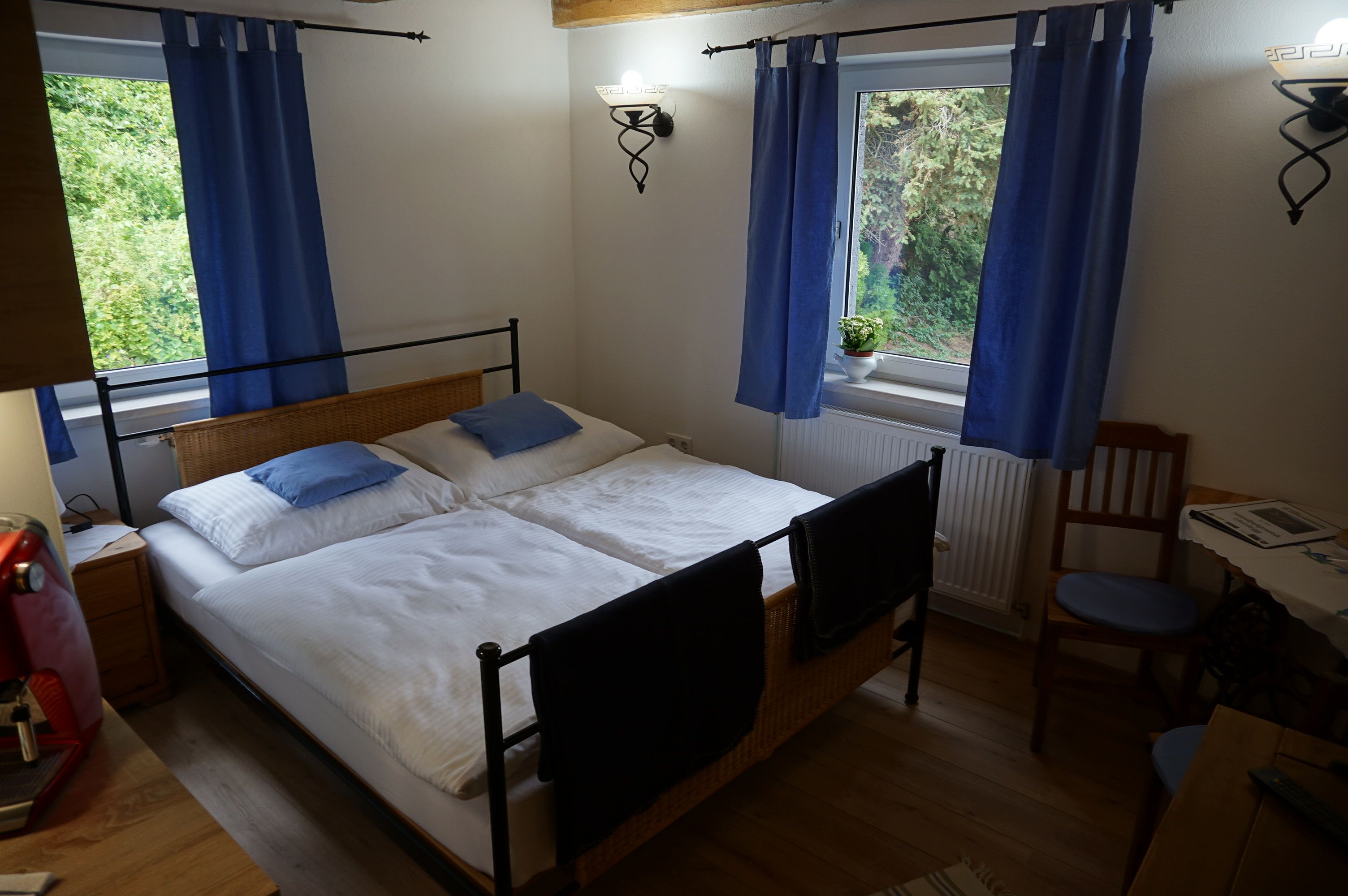 Gemütliches Schlafzimmer mit Doppelbett, blauen Vorhängen und Holzmöbeln.