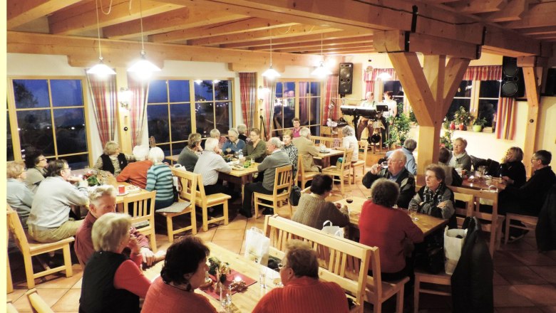 Menschen sitzen in einem gemütlichen Gastraum mit Holzmöbeln und unterhalten sich.