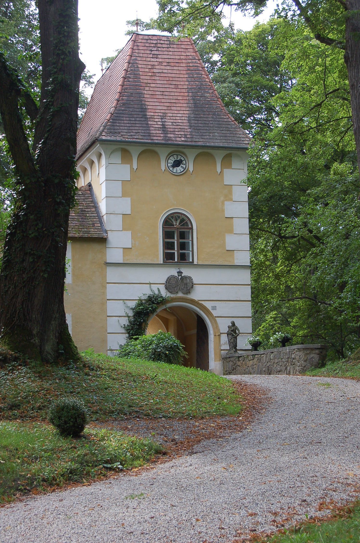 Historisches Gebäude mit Turm und Uhr in einem Waldgebiet.